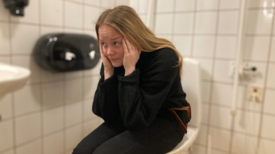 Foto på person med ångest sittandes på en toalettstol
